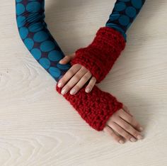 a woman's hands wearing red and blue knitted arm warmers with polka dots