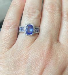 a woman's hand with a ring on it and a blue stone in the middle