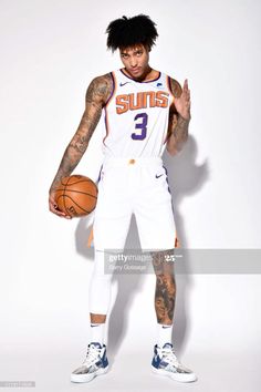 a basketball player holding a ball and posing for the camera with his hands up in front of him