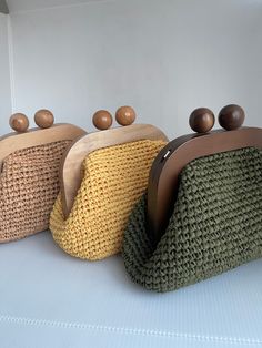 three purses sitting on top of a white table next to each other with wooden handles