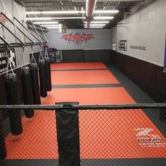 an indoor boxing ring with punching bags on the floor