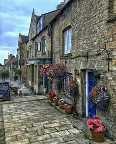 a cobblestone street lined with potted plants and flowers on either side of the building