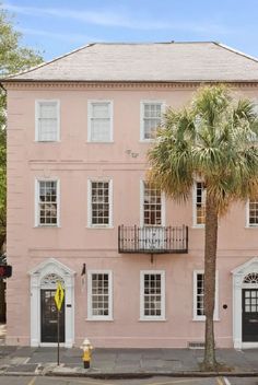 a pink building with white windows and palm tree