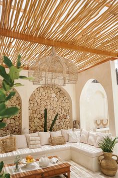 a living room filled with lots of furniture under a wooden roof covered in wicker