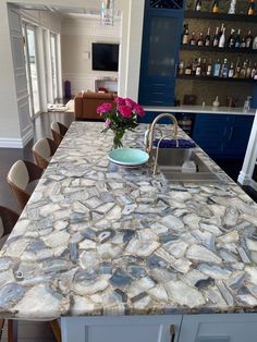 a kitchen island with a bowl of flowers on it and bottles in the back ground