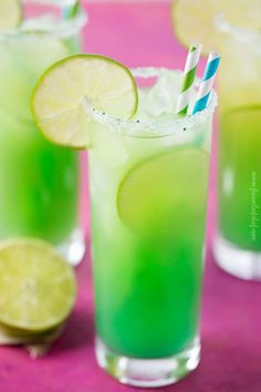 two glasses filled with green liquid and lime slices on the rim, next to each other