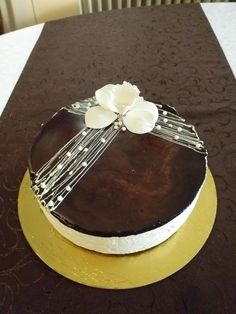 there is a chocolate cake with white flowers on the top and gold plated around it