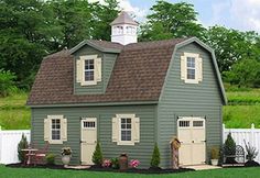 a small green house with two windows and a white picket fence around the front yard