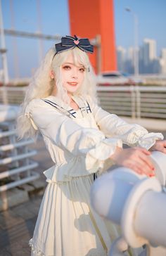 a woman with white hair wearing a sailor outfit and holding onto a telescope while standing on a bridge