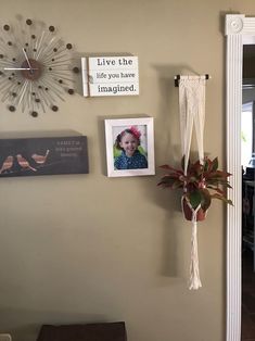 a wall with some pictures on it and a clock hanging from the wall next to a potted plant