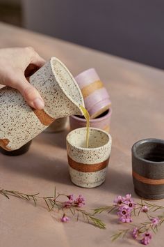 someone pouring coffee into two cups on a table