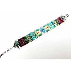 a multi colored bracelet with beads and flowers on the clasp, hanging from a silver chain