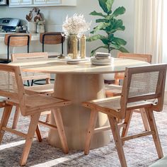 a kitchen table with chairs around it and a potted plant in the center on top