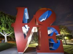 a large red and blue love sculpture sitting in the middle of a park at night