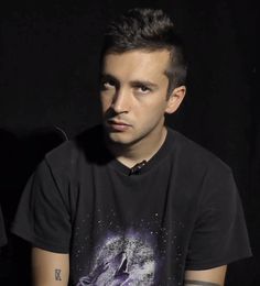 a young man sitting in front of a black background