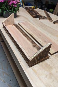 several pieces of wood sitting on top of a wooden table with flowers in the background