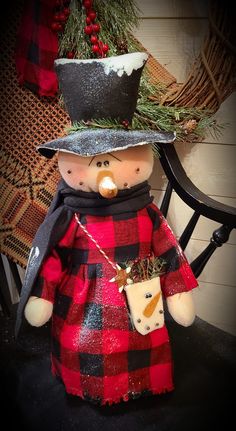 a stuffed snowman wearing a red and black plaid dress with a hat on it's head