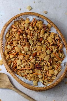 a bowl filled with cereal and nuts next to a wooden spoon on top of a table