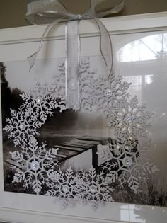 a snowflake photo hanging on a wall with a bow around it's neck