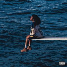 a woman sitting on the edge of a boat in the ocean looking up at the sky