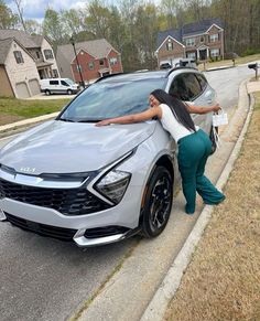 a woman leaning on the hood of a car with her hand on the door handle