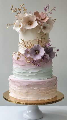 there is a multi layer cake with flowers on the top and bottom tier, decorated in pastel colors