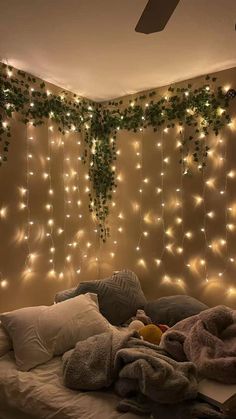 a bed with lights hanging from the ceiling and blankets on it's headboard