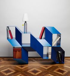 a blue book shelf sitting on top of a hard wood floor next to a lamp