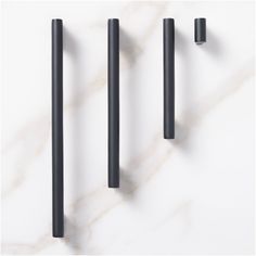 three black handles on a white marble surface