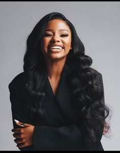 a woman with long black hair smiling and wearing a black blazer over her shoulders