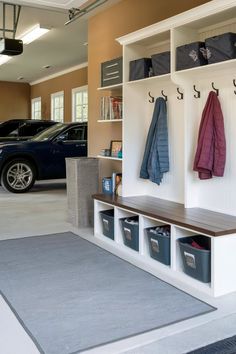 a car is parked in the garage next to some shelves with coats and bags on them