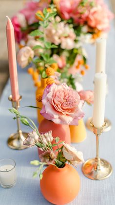 an arrangement of flowers and candles on a table