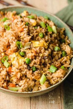 a bowl filled with rice and vegetables on top of a wooden table