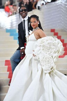 a woman in a wedding dress and a man in a tuxedo pose on the stairs