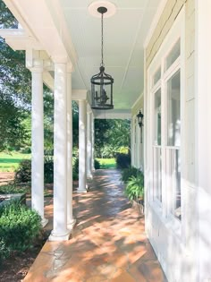 the front porch is lined with white pillars and columns, along with a lantern hanging from the ceiling