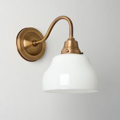 an old fashioned brass wall light with a white glass shade