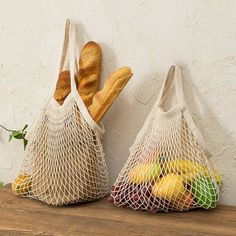 two bags filled with bread sitting on top of a wooden table next to each other