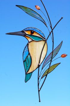 a stained glass bird sitting on top of a tree branch