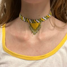 a woman wearing a yellow and black beaded necklace with matching earrings on her neck