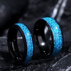 two black rings with blue glitter inlays on them sitting next to each other