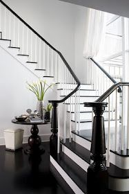 a black and white staircase with flowers on the table next to it, in a home