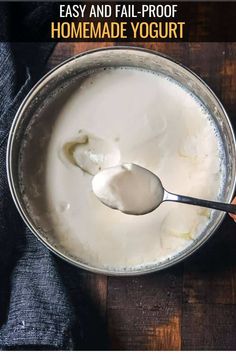 a spoon with yogurt in it on top of a wooden table