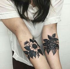 two women with matching tattoos on their arms, one is holding the other's arm