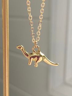 This listing is for one adorable dinosaur charm necklace. Charm is a shiny gold-plated Brachiosaurus (apatosaurus, brontosaurus) Chain measures 16", with a 2" extender chain so that the length can be customized.  Necklace is finished with a gold-filled spring ring clasp. Materials: Charm and chain are gold-plated brass. _ _ _ _ _ _ _ _ _ _ _ _ _ _ _ _ _ _ _ _ _ _ _ _ _ _ _ _ _ _ _ _ _ _ _ _ _ _ _ _ _ _ _ _ _ _ _ _ _ _ _ _ _ _ _ _ * Please read shop policies on returns/cancellations  * Shipping i Novelty Gold Metal Jewelry, Gold Novelty Dangle Jewelry, Novelty Gold Dangle Jewelry, Novelty Gold Pendant Jewelry, Gold Novelty Charm Necklaces For Gifts, Gold Novelty Charm Necklace For Gifts, Handmade Gold Novelty Jewelry, Novelty Gold Jewelry Gift, Novelty Dinosaur Print Jewelry Gift