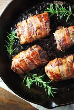 pork chops cooking in a skillet with black sauce and fresh rosemary sprigs