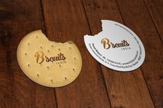 two round cookies sitting on top of a wooden table next to a white paper disc