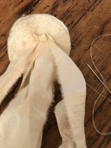 a pair of scissors and a piece of fabric on a wooden table with some thread