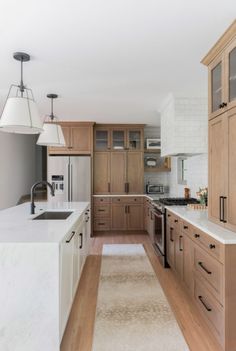 a kitchen with wooden cabinets and marble counter tops, along with a white rug on the floor