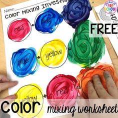 a child's hand is painting different colors on a piece of paper with the words yellow, red, blue and green