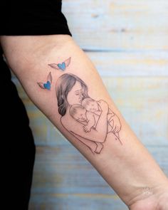 a woman's arm with a drawing of a mother holding her baby on it